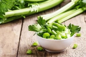 Fresh sliced celery in a white bowl on a vintage wooden backgrou