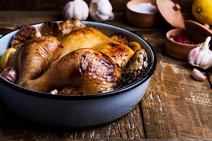 Roast chicken with garlic, thyme and lemon in cooking pan