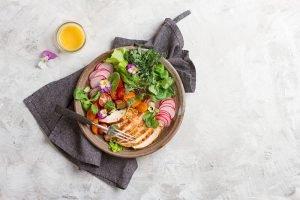 Spring salad with vegetables, chicken breast and edible flowe