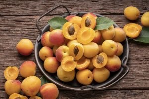 Fresh Apricot fruit with leaf on bamboo mat background, Yellow Apricot on wooden plate over wooden Background.