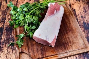 fresh pork loin on a used cutting board resting on an old wooden table